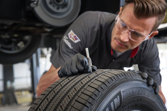 A Cadillac Certified Service Professional checking the tread depth of a tire