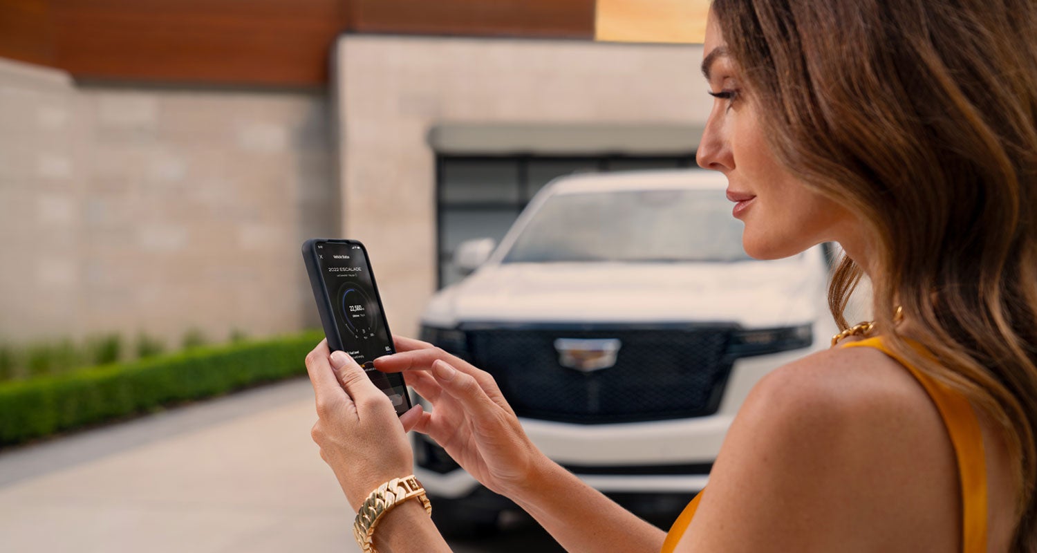 lady checking her mobile with a Cadillac vehicle background | North Bay Cadillac in GREAT NECK NY