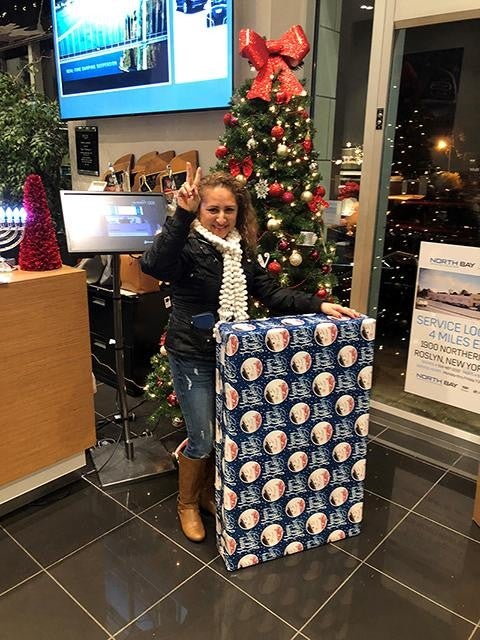 A woman in the North Bay Cadillac lobby standing next to a large wrapped present