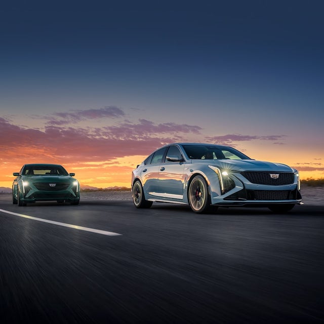Three-Quarters View of Two 2025 Cadillac CT5-V Driving on a Road Under an Evening Sky