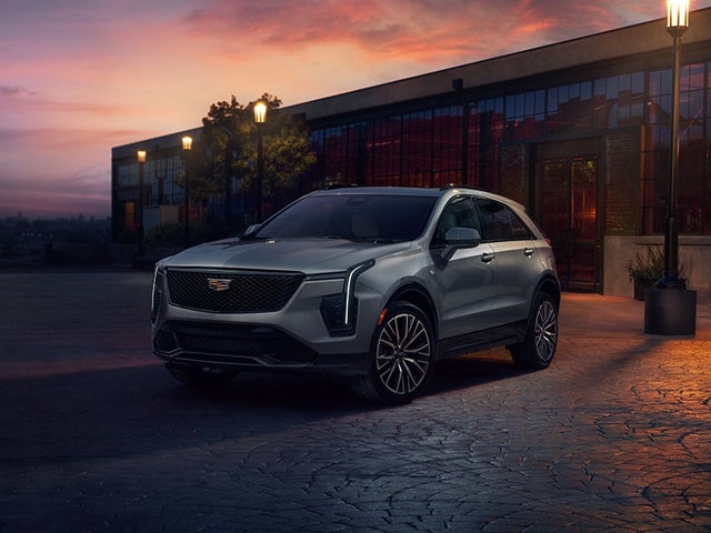 Cadillac XT4 parked outside a building surrounded by lamp posts during a sunset